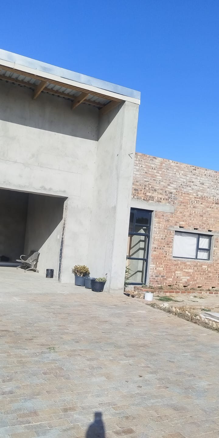 Completed plastered extension with new paving alongside a brick house