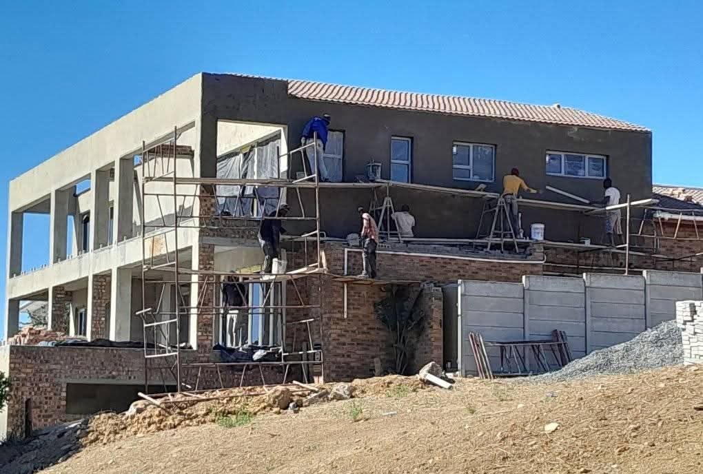 Team plastering the exterior of a double-storey home from scaffolding