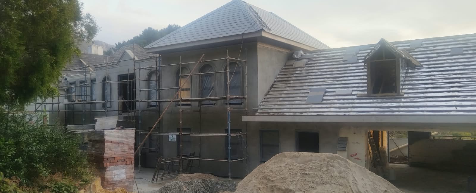 House under scaffolding with a newly tiled roof and plastered walls