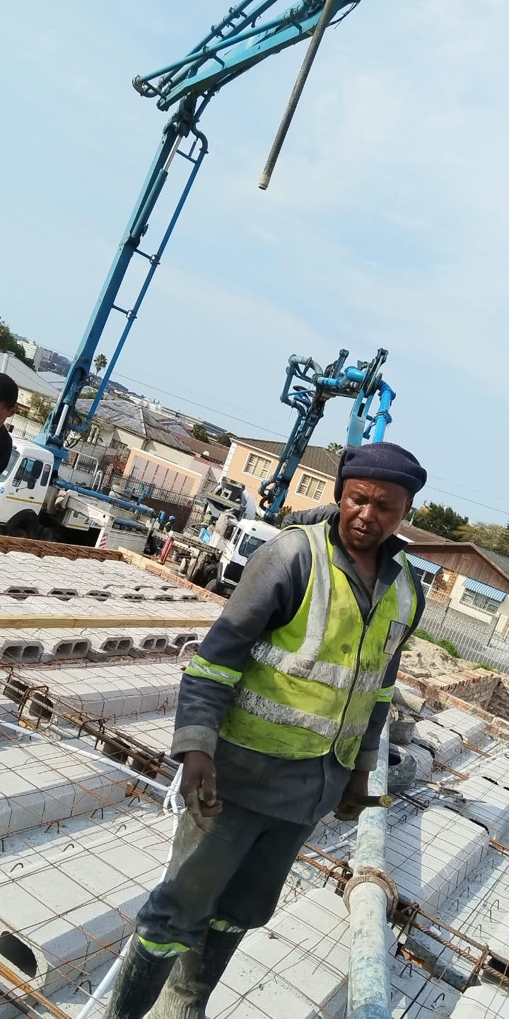 Builder guiding a concrete pump line over a reinforced slab